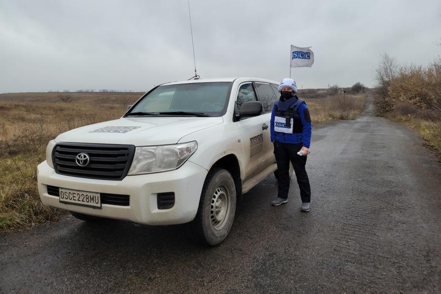 Colleen Ryan, a Masters of Human Rights alumna who works as a  Monitoring Officer for the Organization for Security and Co-operation in Europe’s (OSCE) Special Monitoring Mission to Ukraine, stands next to a car while dressed in her uniform.