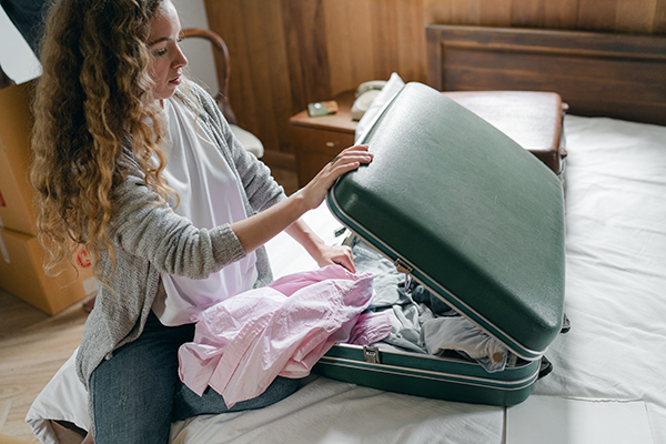 A woman packs her suitcase with clothing items