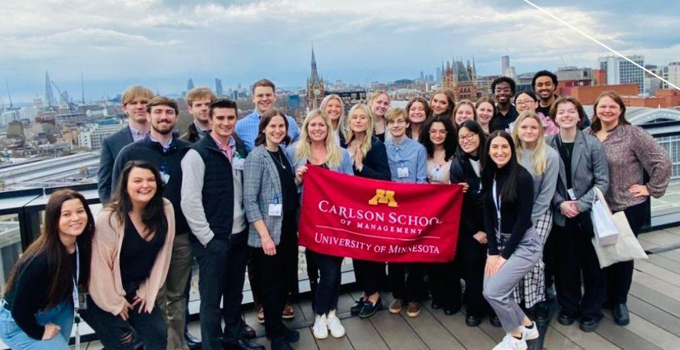 Students hold a Carlson School flag with London in the background