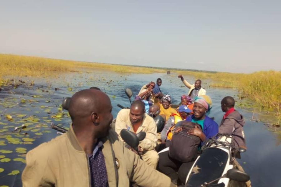 People in Africa riding a boat through a marsh