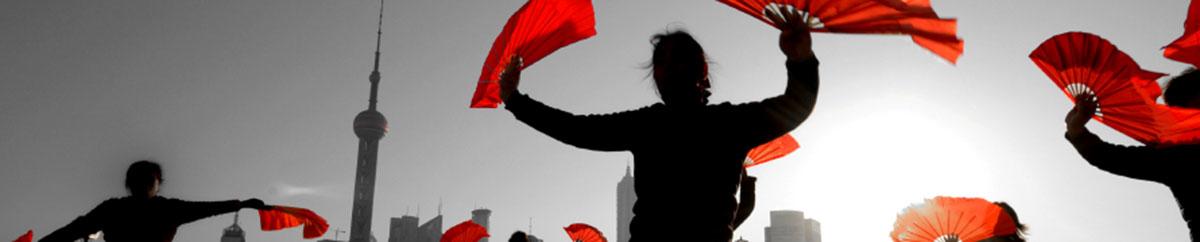 Women dancing with red fans in front of Shanghai skyline