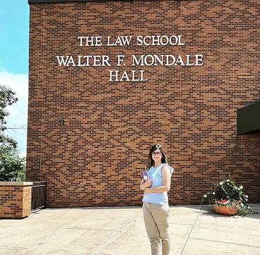 Shaghek holding books in front of the Law School's Walter F. Mondale Hall