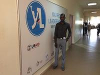 Ibrahima Ngom stands next to a Youth Leadership banner. 