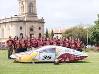 The full Solar Vehicle Project team poses with the car and their trophies.